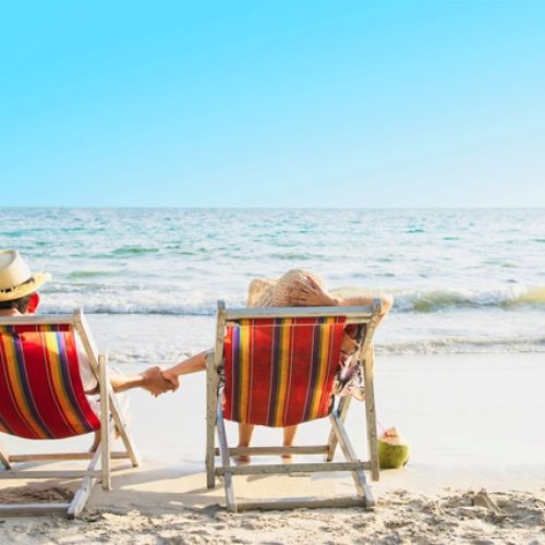 Relax couple lay down on beach chiar with sea wave background - man and woman have vacation at sea nature concept